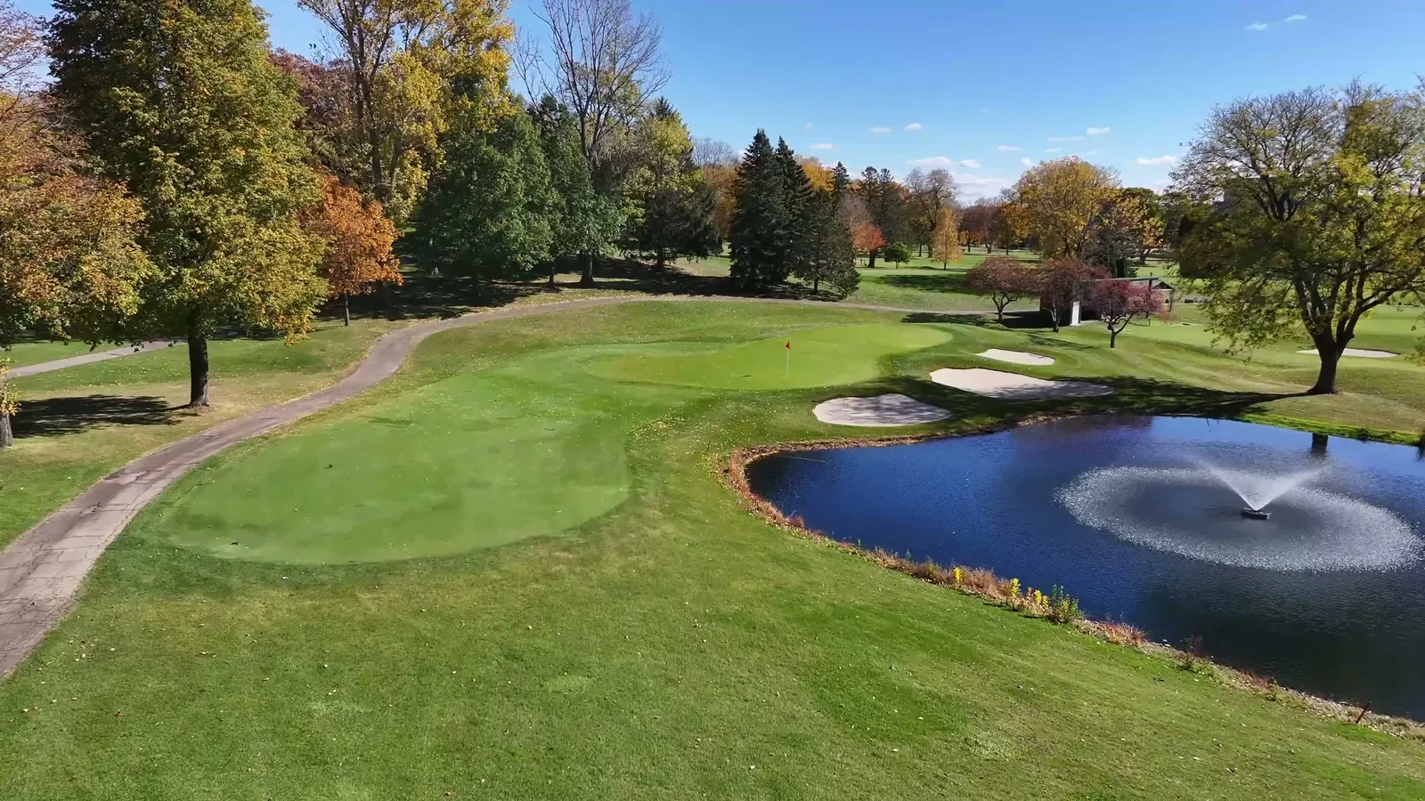 Par 3 green guarded by bunkers and a pond with a fountain on the fifth hole at Blackhawk Country Club