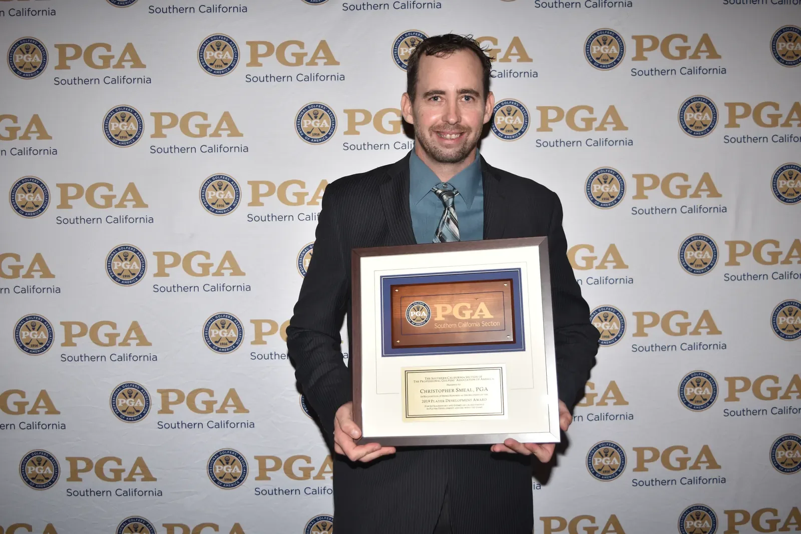 Chris Smeal holds a framed 2019 Player Development Award plaque in front of a Southern California PGA backdrop.