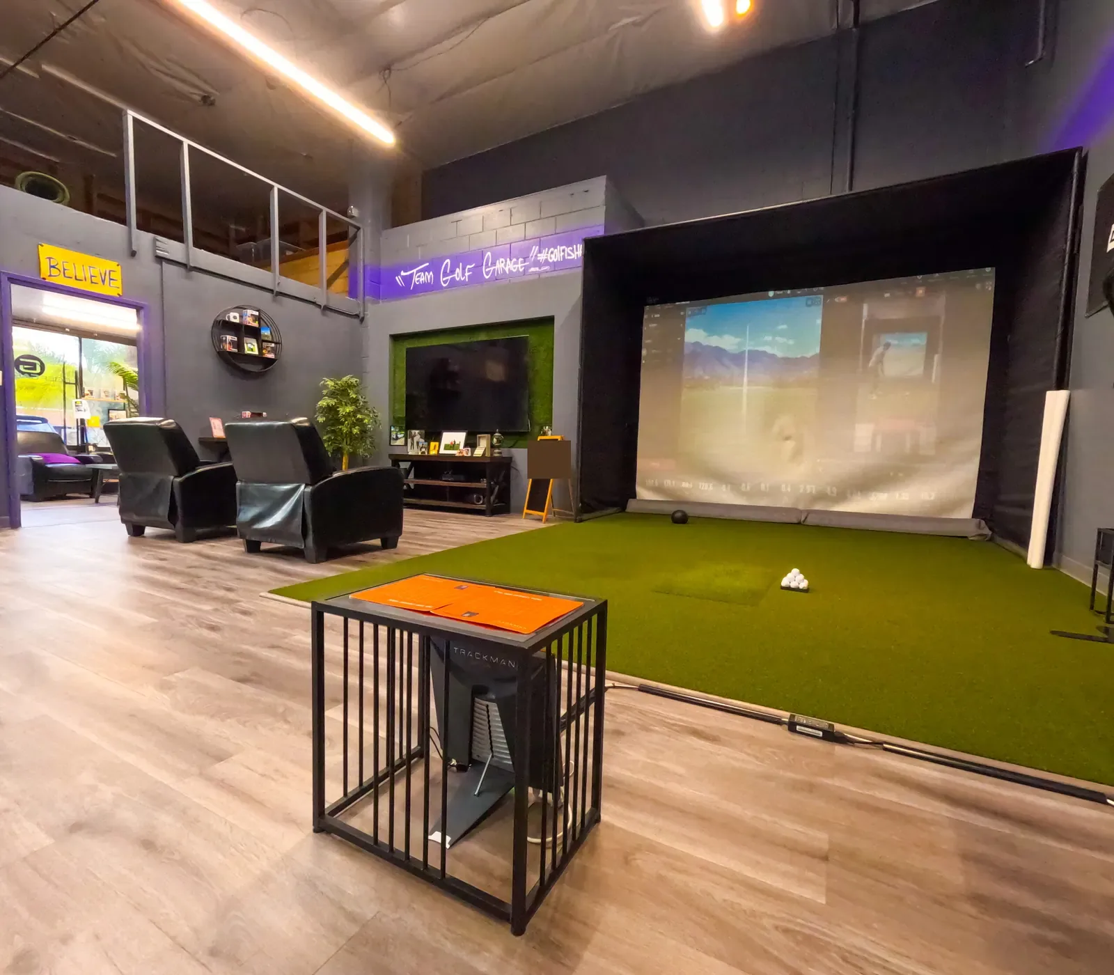 Trackman launch monitor in a metal stand beside the hitting mat at The Golf Garage in San Jose.